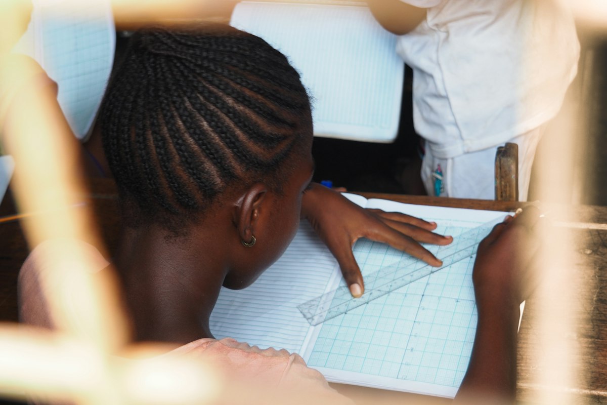 A student drawing a technical diagram with a ruler
